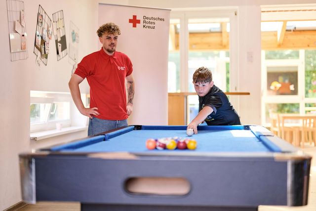 DRK Mitarbeiter und Junge spielen Billard