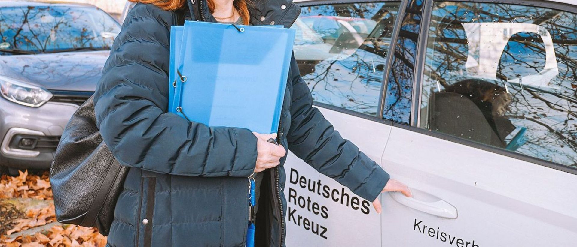 Eine Mitarbeiterin des ambulanten Dienstes öffnet die Tür des Dienstwagens.