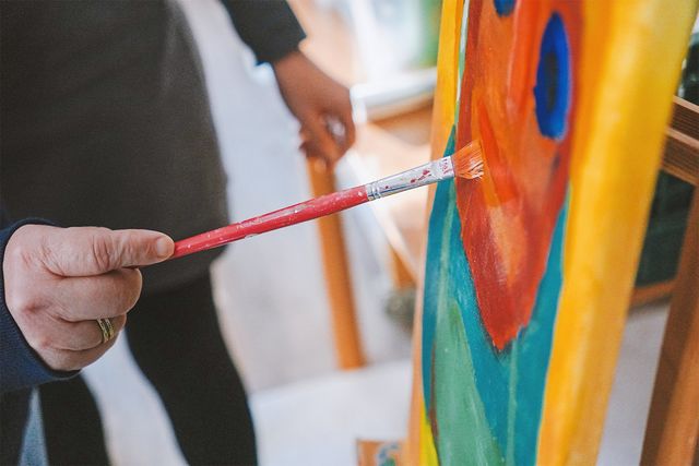 Man sieht, wie mit Pinsel auf Leinwand ein Kunstwerk gezeichnet wird.